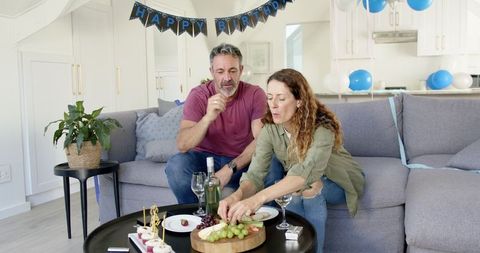 Mature Couple Celebrating Birthday with Wine and Snacks at Home