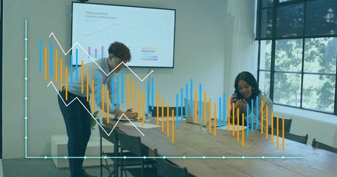 Colleagues collaborating on data presentation in modern meeting room with analytics overlay