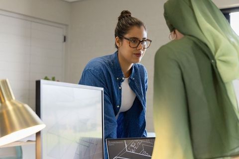 Collaborating on cad: diverse female coworkers reviewing architectural plans on monitors