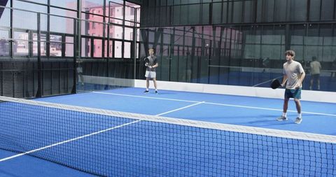 Friends Enjoying Indoor Padel Match on Blue Turf Court