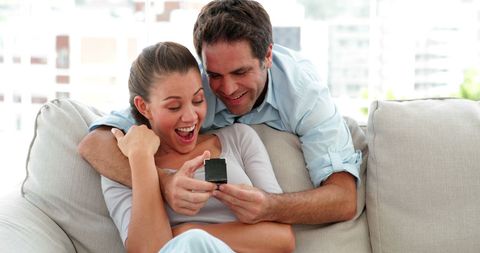 Man Surprising Girlfriend with Gift on Cozy Couch at Home