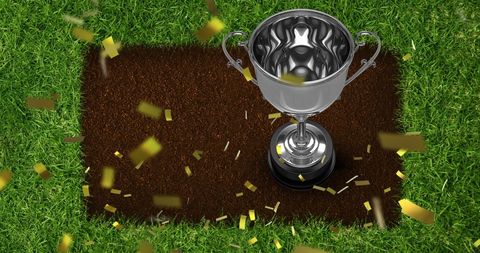 Silver trophy surrounded by gold confetti on green grass