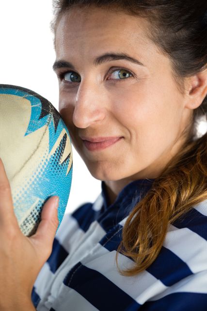Close up portrait of female athlete holding rugby ball against white backgrojnd