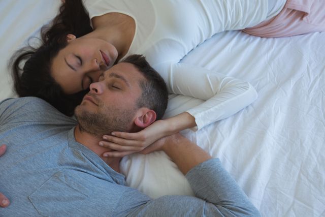 Couple sleeping on bed in bedroom at home