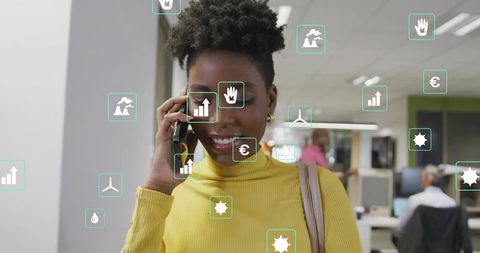 Young professional woman talking on smartphone in open office with floating green icons