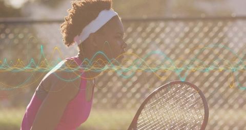 Young woman training on outdoor tennis court gripping racket at golden hour