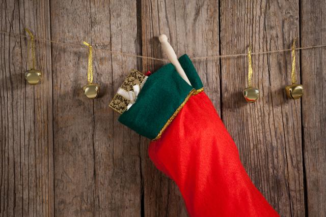 Christmas stocking and bells hanging against wooden wall during christmas time