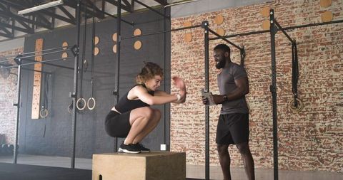 Female athlete performing squat with trainer timing