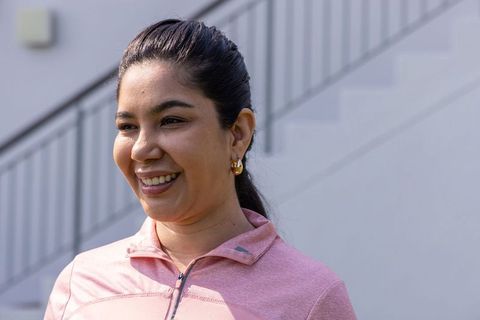 Young asian woman smiling in pink zip-up top outdoors staircase natural light portrait