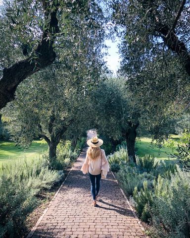 Woman Walking through Lush Garden Pathway in Autumn