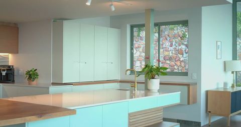 Bright Modern Kitchen Island with Glossy Countertop, Brass Faucet and Aqua Cabinets