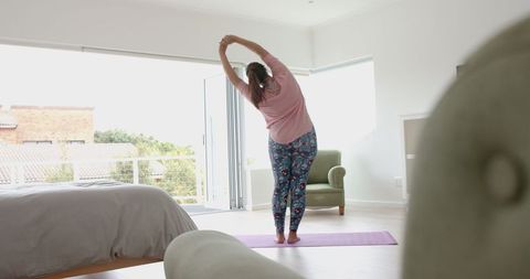 Plus Size Woman Practicing Yoga at Home in Bright Room