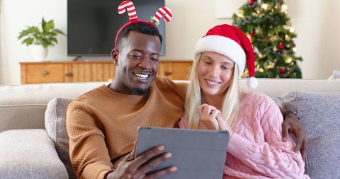 Cheerful Couple Celebrating Christmas at Home, Using Tablet