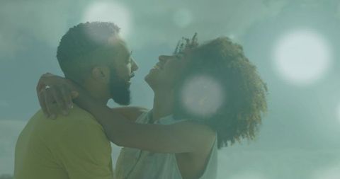 Black couple embracing and leaning back under sunlit sky with soft lens flare