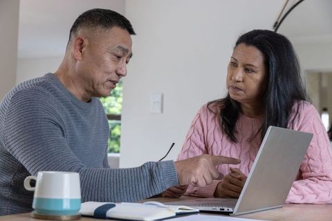 Senior couple discussing with laptop at home