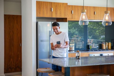 Man Holding Smartphone in Modern Kitchen with Marble Island