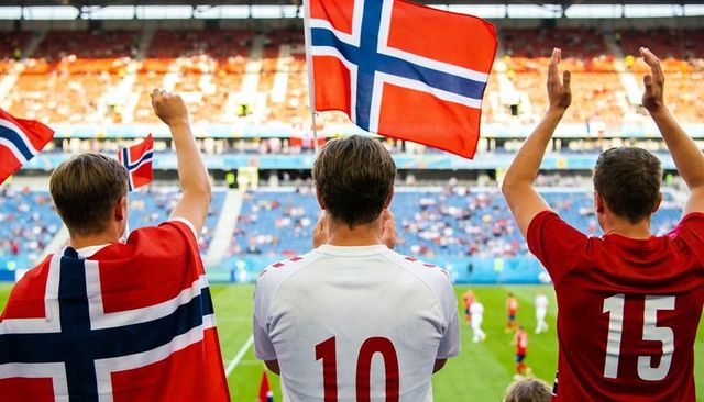 Norwegian football fans cheering and waving flags in stadium during international match