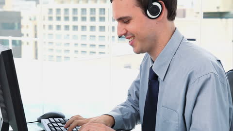 Smiling Businessman Wearing Headset Typing on Keyboard