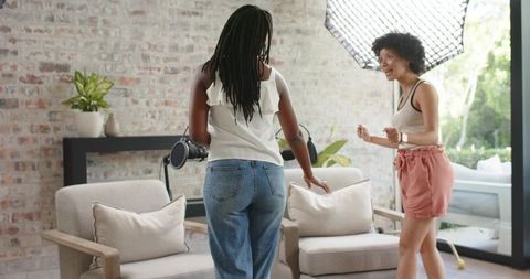 Two african american women chatting in bright home studio with softbox and exposed brick wall