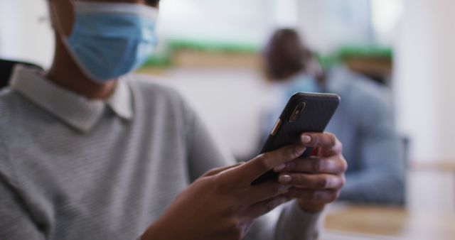 Person wearing face mask using smartphone in office - Download Free Stock Images Pikwizard.com