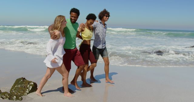 Diverse group of friends walking together on sandy beach, laughing and enjoying sunny summer day. Ideal for images related to friendship, leisure, travel, summer vacations, youth, outdoor activities, happiness and capturing fun moments.