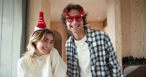 Happy friends posing with christmas accessories in cozy living room