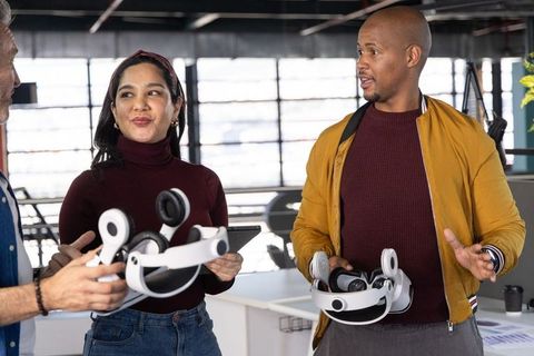 Diverse team testing mixed reality headsets and collaborating in modern open office