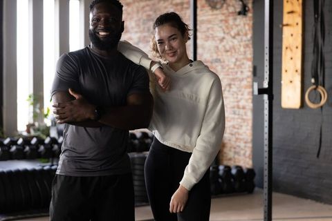 Smiling black man and asian woman posing and training together in industrial gym, teamwork
