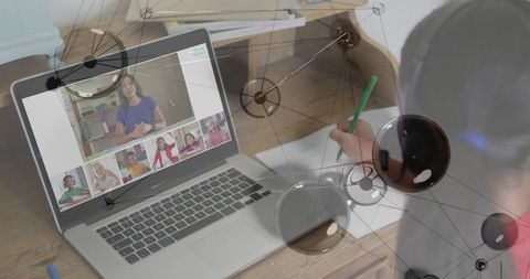 Schoolgirl writing during online class with laptop video conference and network overlay