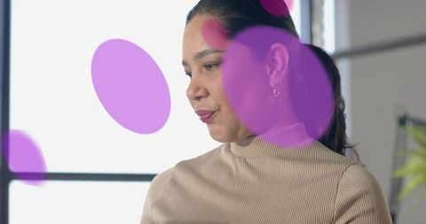 Latina professional facing side wearing beige turtleneck with magenta overlays
