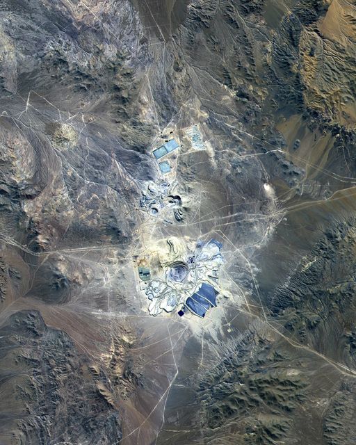 This ASTER image covers 30 by 37 km in the Atacama Desert, Chile and was acquired on April 23, 2000. The Escondida Cu-Au-Ag open-pit mine is at an elevation of 3050 m, and came on stream in 1990. Current capacity is 127,000 tons/day of ore; in 1999 production totaled 827,000 tons of copper, 150,000 ounces of gold and 3.53 million ounces of silver. Primary concentration of the ore is done on-site; the concentrate is then sent to the coast for further processing through a 170 km long, 9 pipe. Escondida is related geologically to three porphyry bodies intruded along the Chilean West Fissure Fault System. A high grade supergene cap overlies primary sulfide ore. This image is a conventional 3-2-1 RGB composite. Figure 1 displays SWIR bands 4-6-8 in RGB, and highlights lithologic and alteration differences of surface units. The image is located at 24.3 degrees south latitude and 69.1 degrees west longitude.  http://photojournal.jpl.nasa.gov/catalog/PIA11090