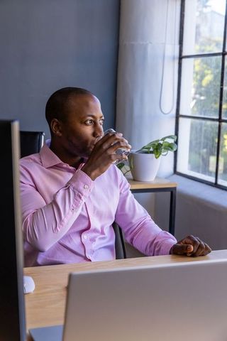 African american businessman drinking water at office desk