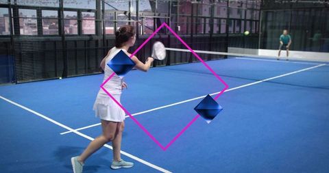 Female tennis player swinging forehand on urban blue court with modern glass backdrop