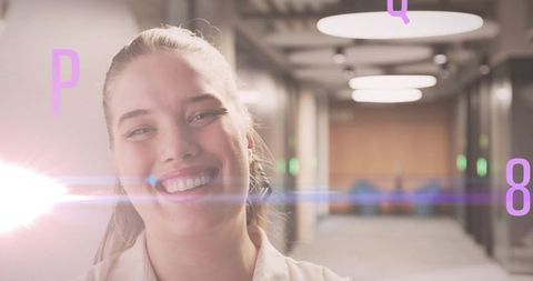 Smiling woman in futuristic office corridor with floating letters