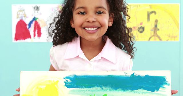 Smiling Young Girl Holding Colorful Artwork in Classroom - Download Free Stock Images Pikwizard.com