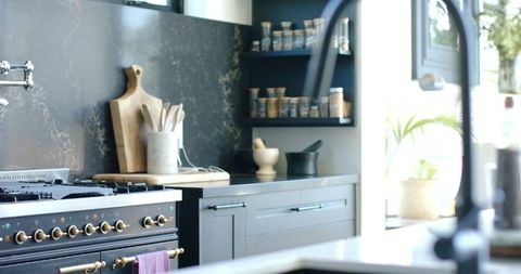 Black range anchoring modern kitchen with brass knobs, wooden utensils and spice jars