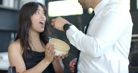 Playful feeding moment between couple in modern kitchen during date night sharing dessert