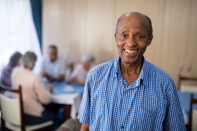 Smiling Senior Man in Nursing Home with Friends in Background - Download Free Stock Photos Pikwizard.com