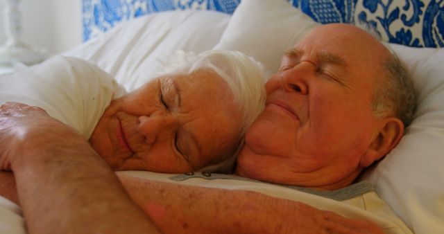 Close-up of Caucasian senior couple sleeping on bed in bedroom at comfortable home. They are embracing each other 4k