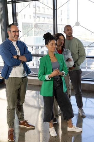 Diverse professional team standing in modern glass atrium, african american woman leading