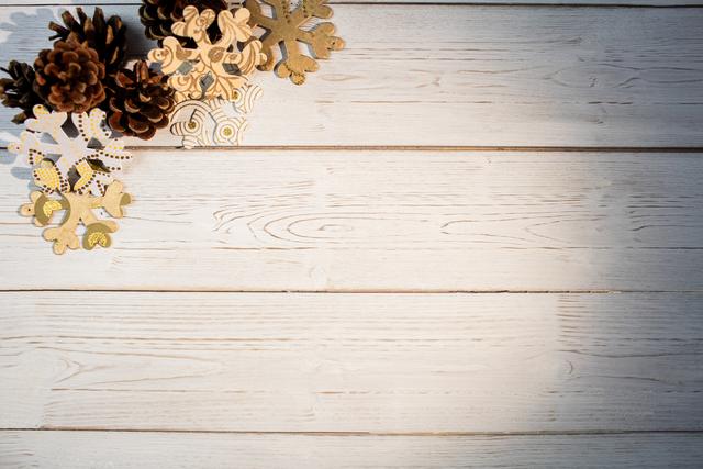 Christmas snowflakes and pine cones arranged on a wooden plank. Ideal for holiday greeting cards, festive invitations, seasonal advertisements, and winter-themed designs. Perfect for adding a rustic and natural touch to Christmas and winter projects.