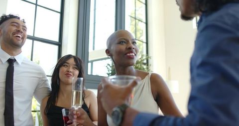 Diverse friends enjoying cocktails and conversation in modern sunlit living room