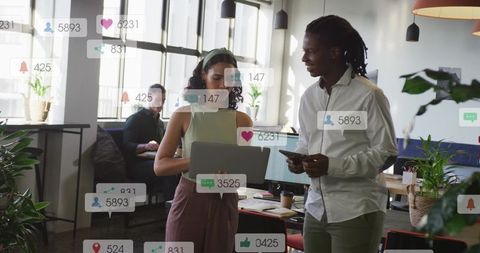 Young Professionals Discussing Project with Laptop and Tablet in Bright Coworking Space