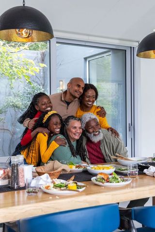 Multigenerational african american family gathering and sharing warm meal in modern dining