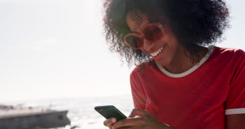 Joyful Woman Texting with Smartphone by Ocean