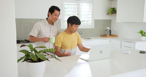 Father and Son Bonding Over Laptop in Modern Kitchen Environment
