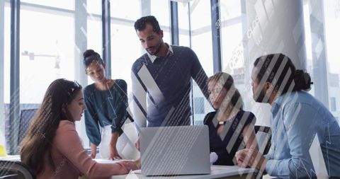 Diverse Team Brainstorming Around Laptop in Modern Meeting Room