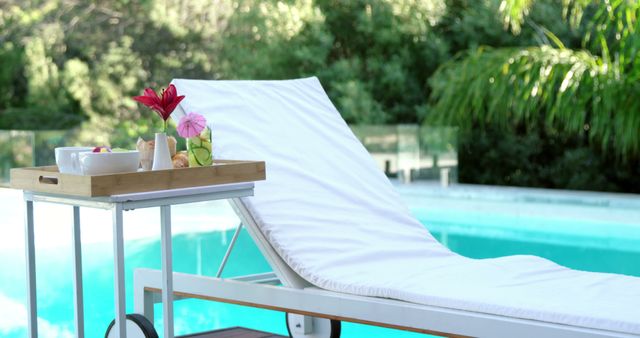 Poolside scene with comfortable chaise lounge and tray of refreshments featuring flowers. Ideal for illustrating concepts of summer leisure, luxury vacations, and relaxation. Perfect for travel brochures, resort advertisements, and lifestyle magazines.