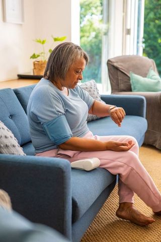 Senior woman checking blood pressure at home for wellness