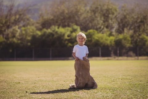 Boy Enjoying Outdoors with Burlap Sack on Sunny Lawn